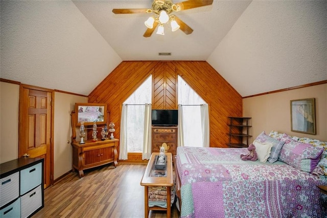 bedroom featuring visible vents, light wood-style flooring, wood walls, and vaulted ceiling