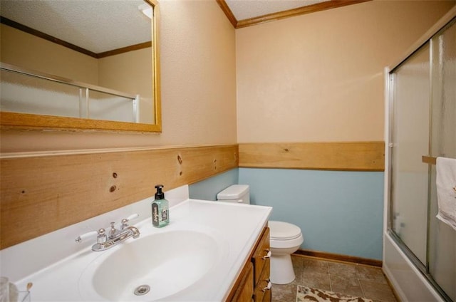 full bathroom featuring toilet, a textured ceiling, combined bath / shower with glass door, crown molding, and vanity