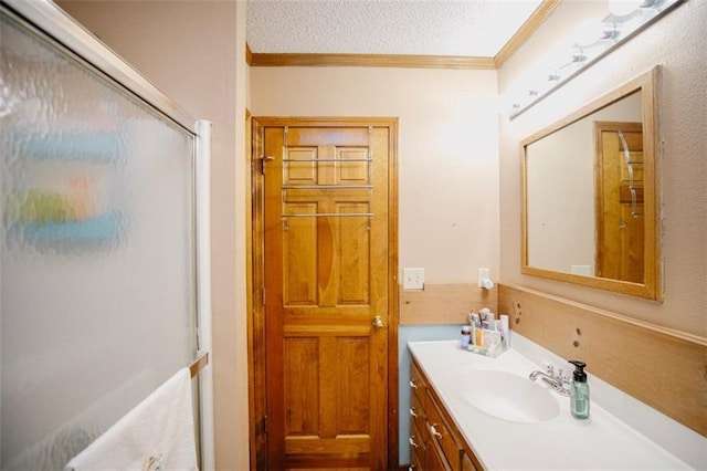 full bath with an enclosed shower, a textured ceiling, ornamental molding, and vanity