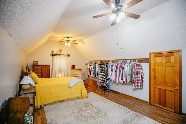 bedroom featuring a ceiling fan, vaulted ceiling, wood finished floors, and a textured ceiling