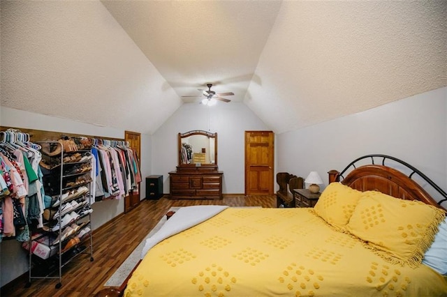 bedroom featuring ceiling fan, vaulted ceiling, wood finished floors, and a textured ceiling