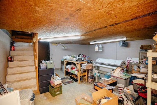 finished basement featuring tile patterned floors, stairway, and concrete block wall