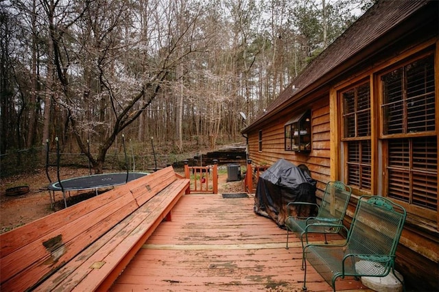 wooden terrace featuring a trampoline and a grill