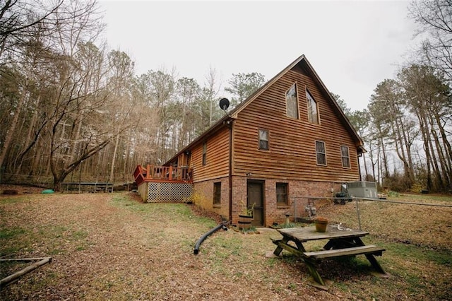 view of home's exterior featuring a wooden deck, brick siding, and fence