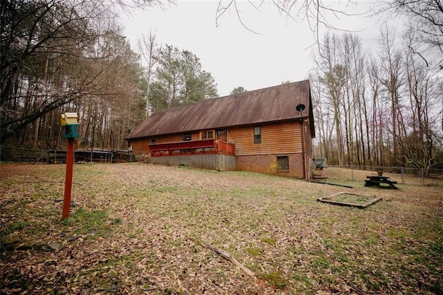 view of home's exterior with a yard, a trampoline, a deck, and fence