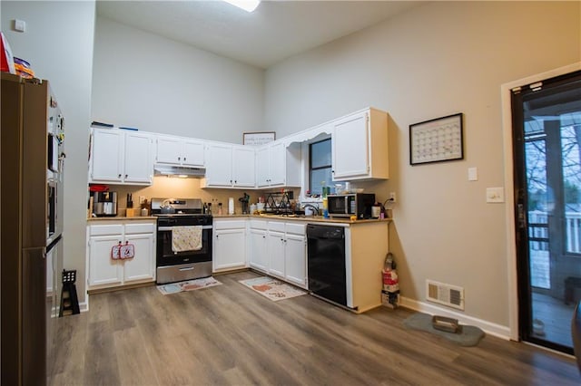 kitchen featuring stainless steel appliances, visible vents, a high ceiling, white cabinetry, and under cabinet range hood