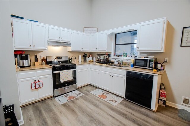 kitchen featuring white cabinets, under cabinet range hood, stainless steel appliances, and light countertops