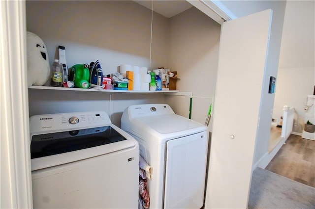 clothes washing area featuring laundry area, independent washer and dryer, baseboards, and wood finished floors