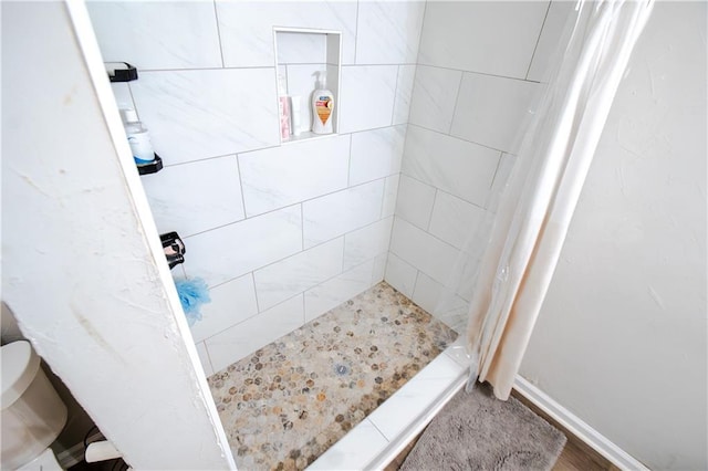 full bath with toilet, a shower stall, and baseboards