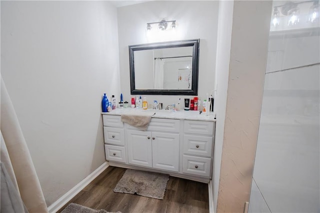 bathroom with wood finished floors, vanity, and baseboards