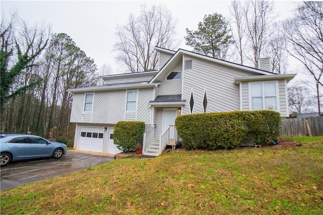 view of side of home featuring aphalt driveway, an attached garage, fence, a lawn, and a chimney