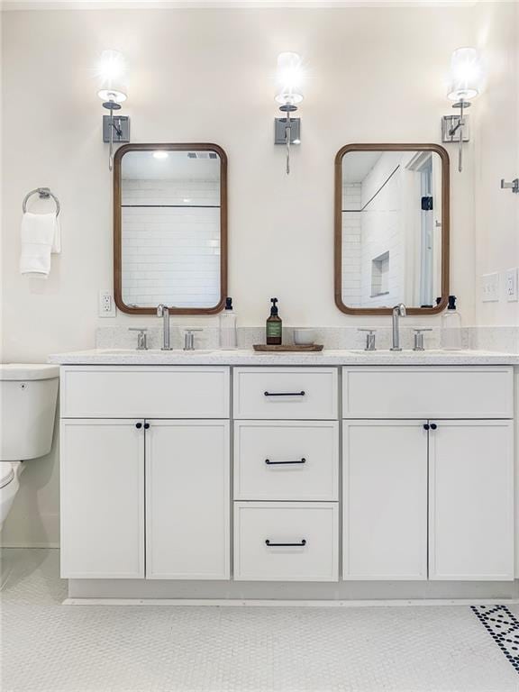 bathroom featuring double vanity, tile patterned flooring, a sink, and toilet