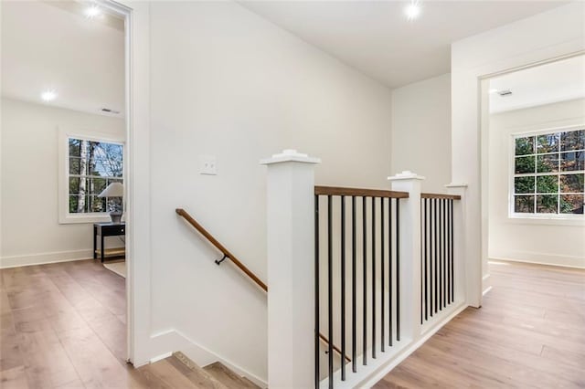 interior space with baseboards, a healthy amount of sunlight, an upstairs landing, and light wood-style floors