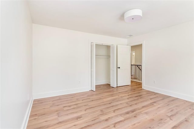 unfurnished bedroom with a closet, light wood-style flooring, and baseboards