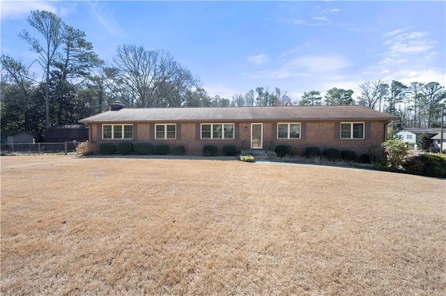 single story home featuring brick siding, a chimney, a front yard, and fence