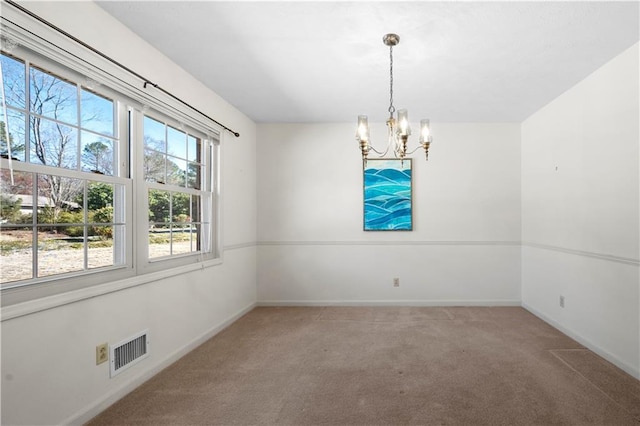 empty room with a chandelier, carpet floors, visible vents, and baseboards