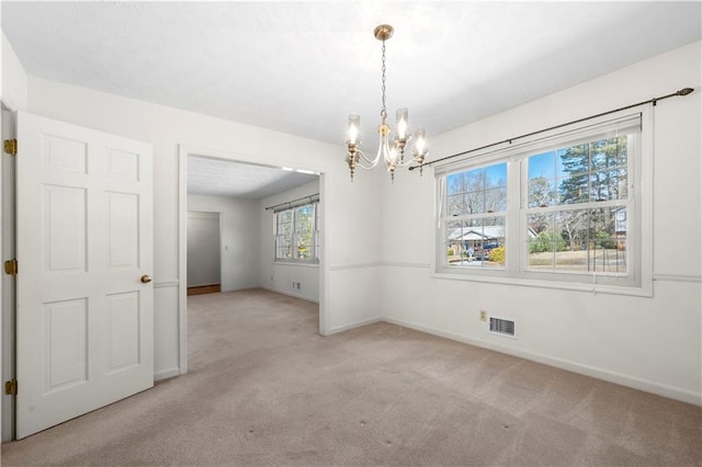 spare room with visible vents, a notable chandelier, light carpet, and baseboards