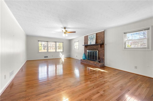 unfurnished living room with visible vents, a textured ceiling, a fireplace, and hardwood / wood-style flooring