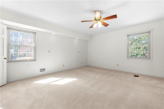 unfurnished room featuring light colored carpet, visible vents, ceiling fan, and baseboards