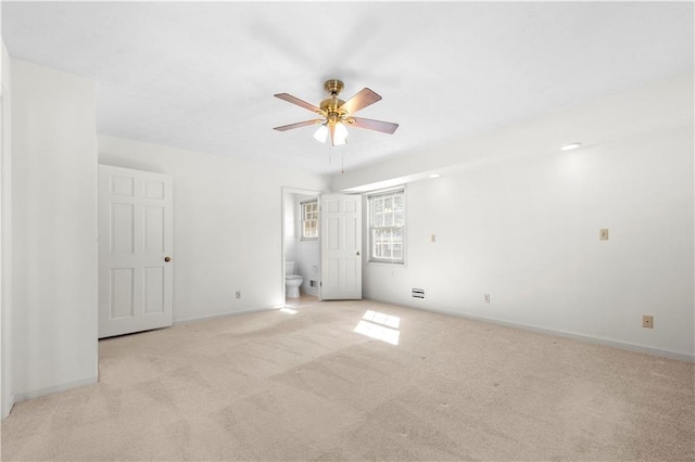 spare room with light carpet, ceiling fan, and baseboards