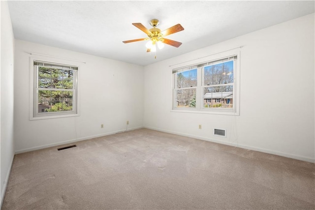 spare room featuring visible vents, ceiling fan, light carpet, and baseboards