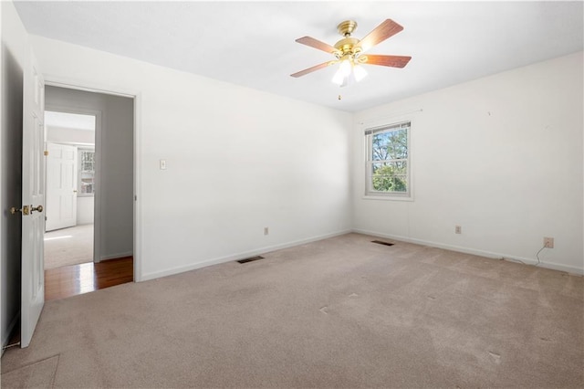 empty room with ceiling fan, carpet flooring, visible vents, and baseboards