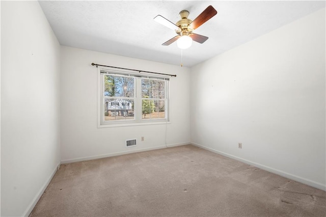 empty room with ceiling fan, carpet flooring, visible vents, and baseboards