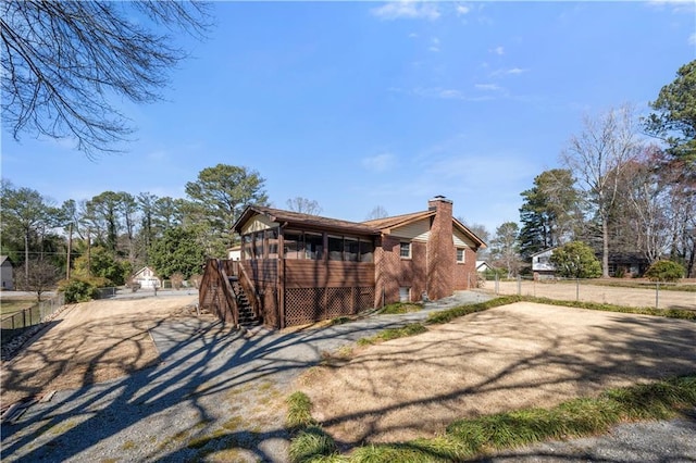 view of side of property with fence, driveway, a chimney, and stairs