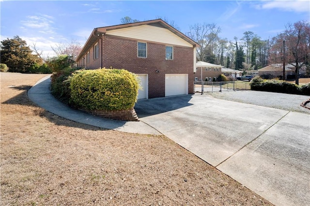 view of side of home featuring a garage, driveway, and brick siding