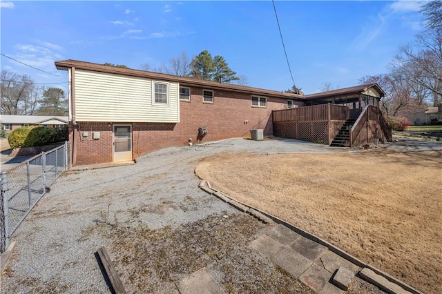 back of house featuring a deck, brick siding, fence, and stairway