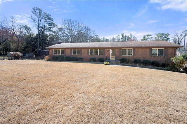 ranch-style house with a front yard, brick siding, fence, and a chimney