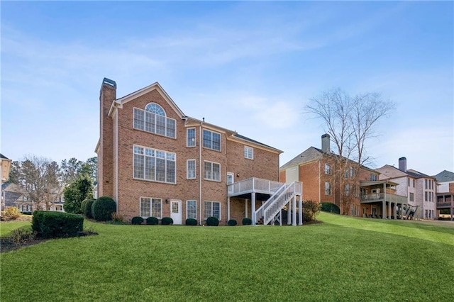 back of property with a deck, brick siding, stairs, a yard, and a chimney