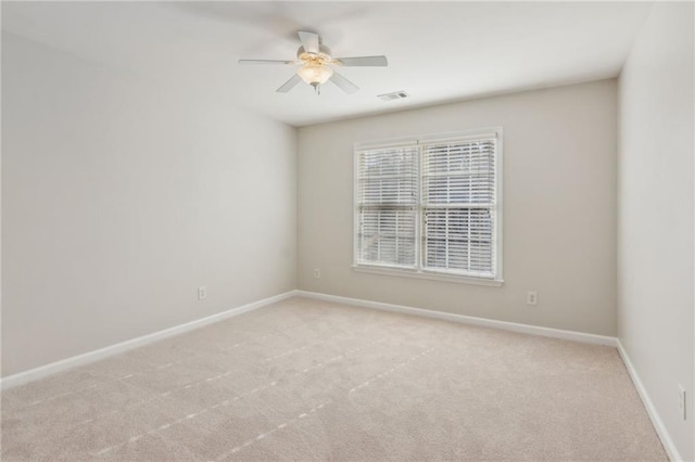 spare room with a ceiling fan, visible vents, light carpet, and baseboards