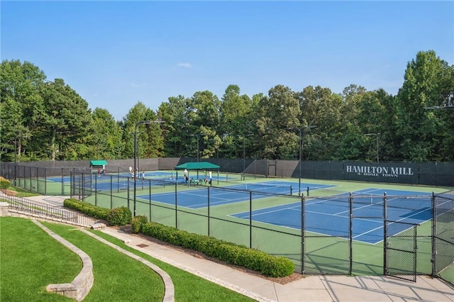 view of sport court featuring fence and a lawn