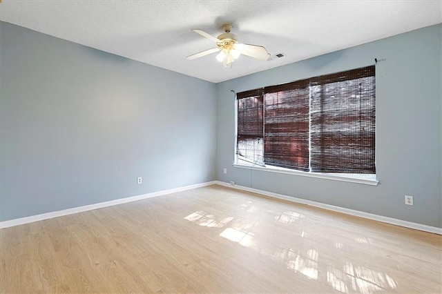 spare room with light wood-type flooring, ceiling fan, and a textured ceiling