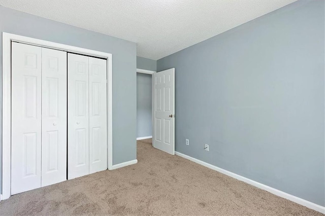 unfurnished bedroom with a textured ceiling, a closet, and light colored carpet