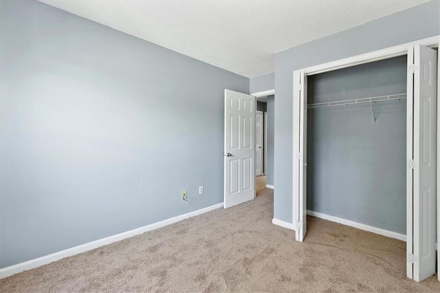 unfurnished bedroom with light carpet, a closet, and a textured ceiling