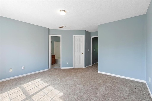 unfurnished bedroom featuring ensuite bathroom and light carpet