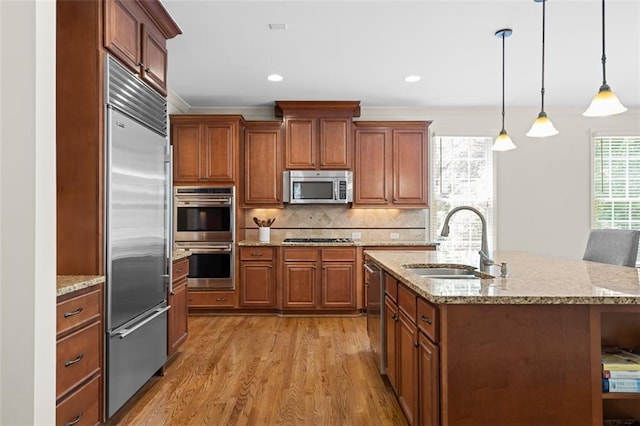 1215 Renaissance Ct SE, Mableton, GA 30126 - kitchen featuring stainless steel appliances, light wood-style flooring, decorative backsplash, hanging light fixtures, and an island with sink