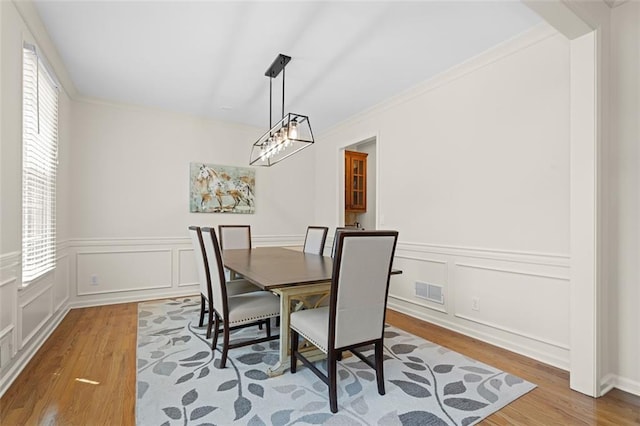 1215 Renaissance Ct SE, Mableton, GA 30126 - dining space featuring wood finished floors, a decorative wall, ornamental molding, and wainscoting