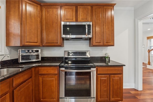 183 Whitefoord Ave NE, Atlanta, GA 30307 - kitchen with stainless steel appliances, a sink, dark wood-type flooring, brown cabinetry, and ornamental molding