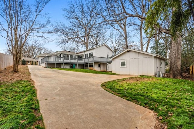 view of front facade with a front yard, fence, board and batten siding, and driveway