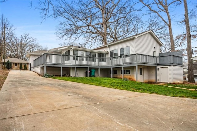 view of front of home with a deck, concrete driveway, and a front yard