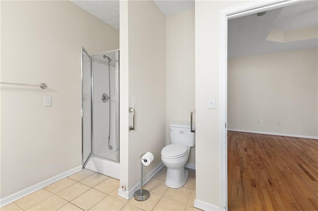 full bath featuring a stall shower, tile patterned flooring, baseboards, and toilet