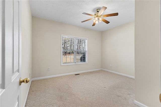 carpeted empty room with a ceiling fan, visible vents, and baseboards