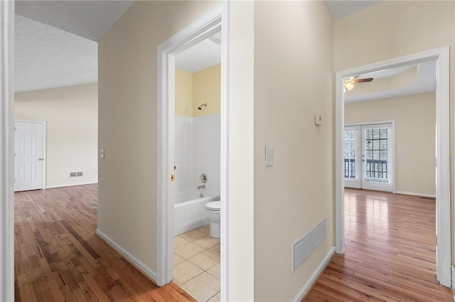 corridor featuring wood finished floors, visible vents, and baseboards