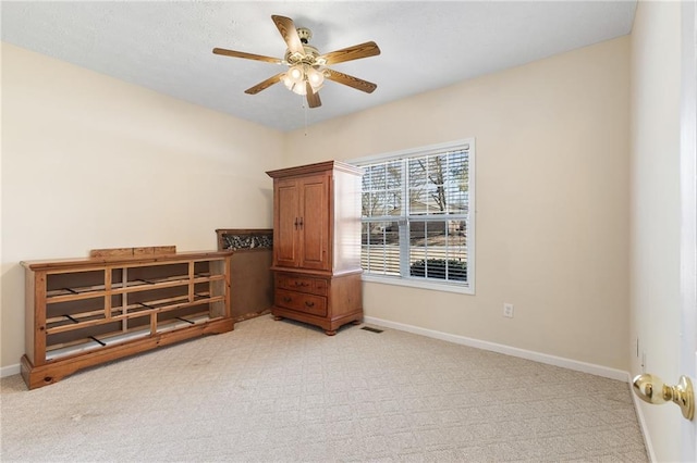 interior space with ceiling fan, light colored carpet, and baseboards