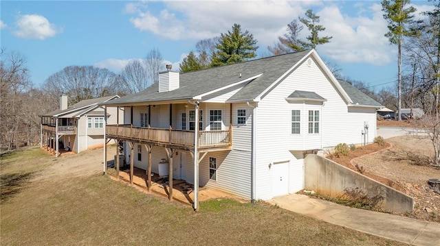 back of house featuring driveway, a yard, a chimney, and a wooden deck