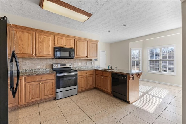 kitchen featuring light tile patterned floors, decorative backsplash, a peninsula, black appliances, and a sink