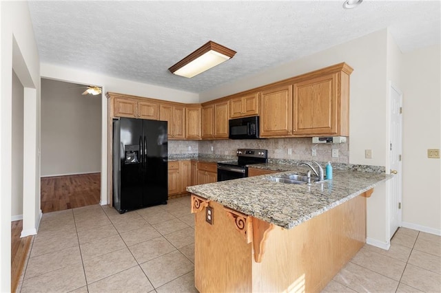 kitchen featuring a peninsula, black appliances, light tile patterned floors, and a sink